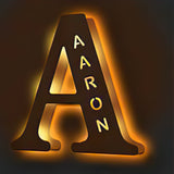 Custom wooden letter "A" night light with engraved name "AARON", emitting a warm, soft glow. Perfect personalized gift.